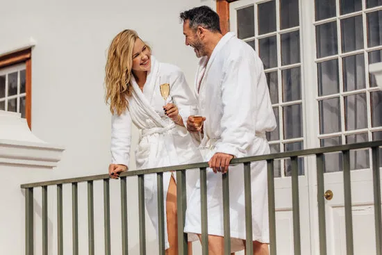 Couple in bathrobes drinking wine on balcony