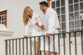Couple in bathrobes drinking wine on balcony